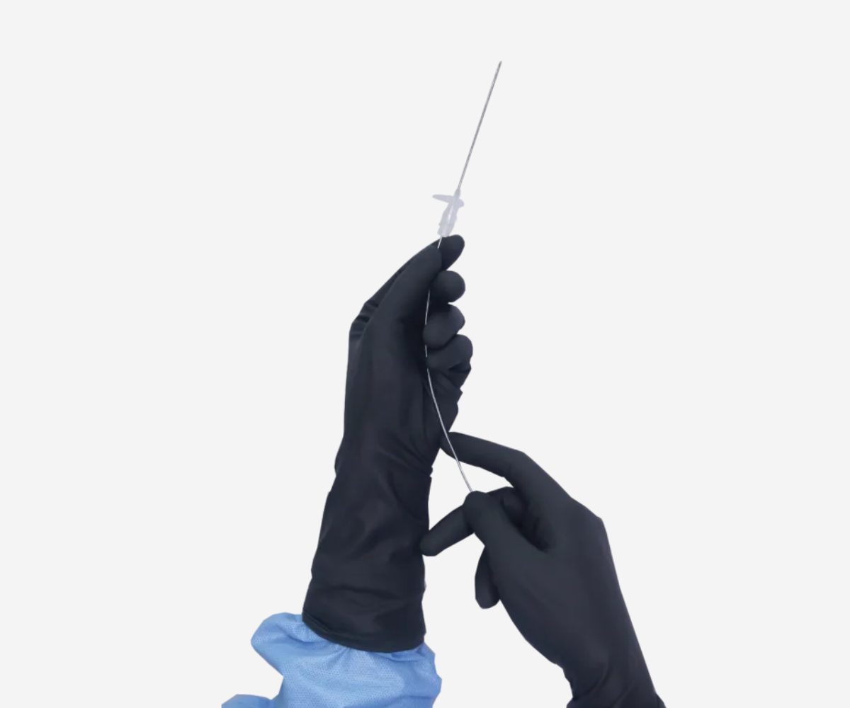 Hands wearing black IneoGuard radiation attenuating surgical gloves holding a medical guidewire